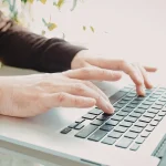 Dłonie przedsiębiorcy piszące na laptopie, symbolizujące zakup zagranicznego oprogramowania SaaS i licencji objętych podatkiem u źródła WHT.