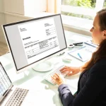 Księgowa analizująca e-fakturę na monitorze komputera, co ilustruje proces wdrażania i audytu obowiązkowego systemu KSeF w firmie.