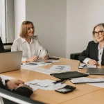 Zgromadzenie wspólników w spółce z o.o. dyskutujące nad dokumentami przy stole konferencyjnym, co ilustruje proces zamknięcia roku i zatwierdzenia sprawozdania finansowego.