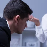 Zestresowany pracownik podczas trudnej rozmowy z przełożoną - ilustracja problemu mobbingu w pracy po nowelizacji Kodeksu pracy.